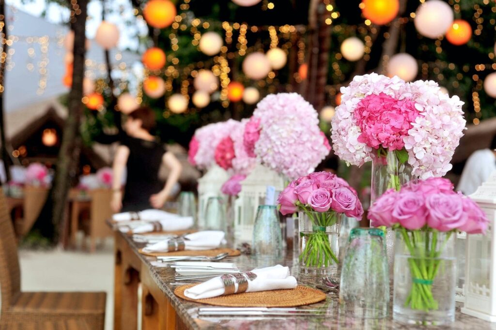 Pink flowers sit on an elegantly decorated table at an outdoor wedding