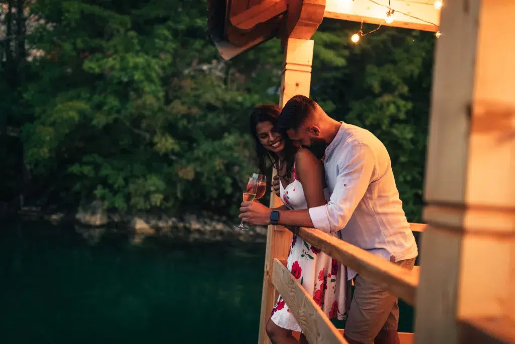 Couple on balcony of weekend cottage near lake, hugging