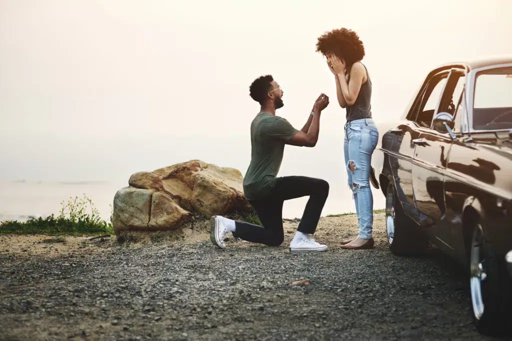 Shot of a young man proposing to his girlfriend during a road trip