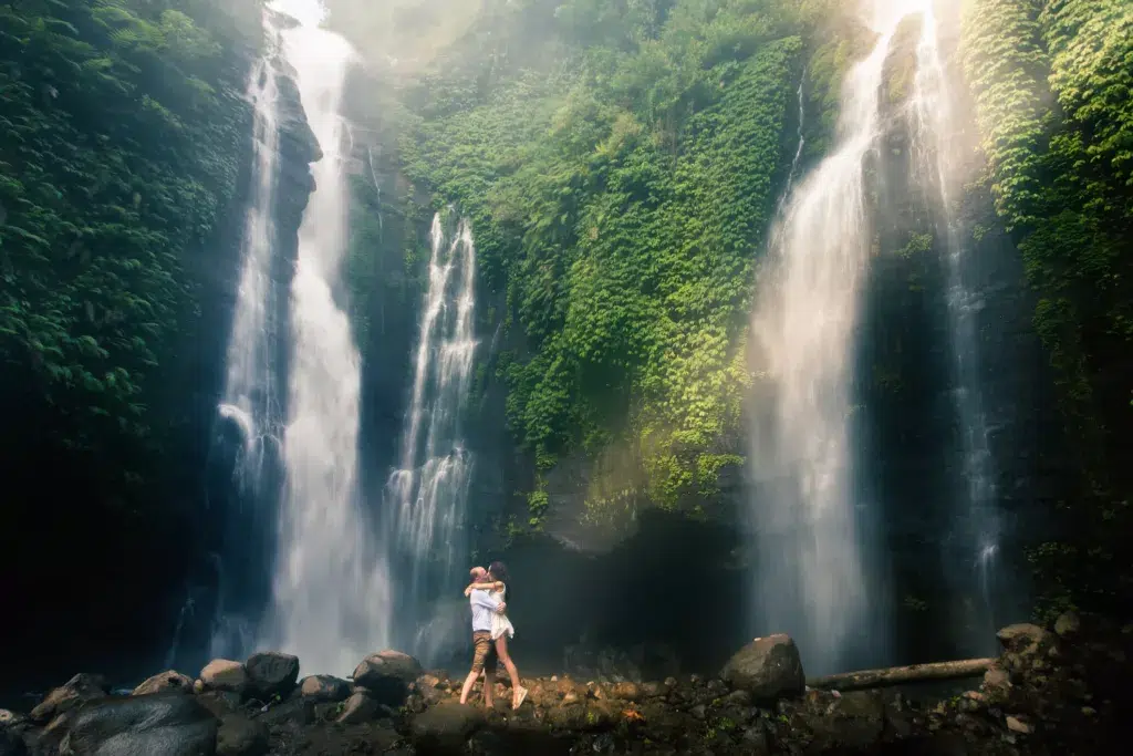 Amazing romantic view of happy couple near a beautiful grand waterfall in the jungle.