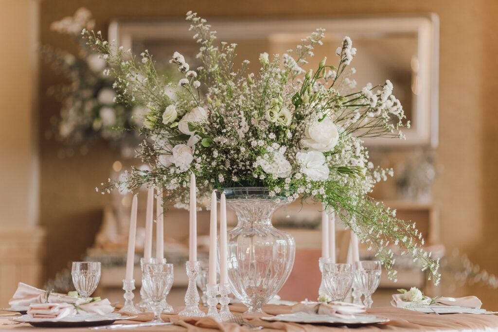 A decorative bouquet as a centerpiece on a table, surrounded by unlit candles