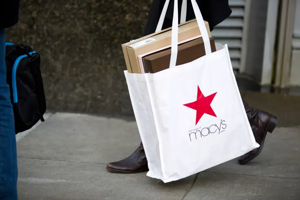 A man walks with a Macy's bag in hand