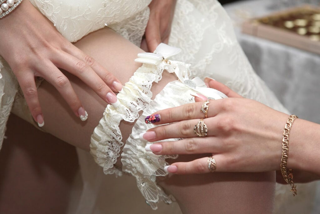 A bridesmaid helps the bride put on the garter