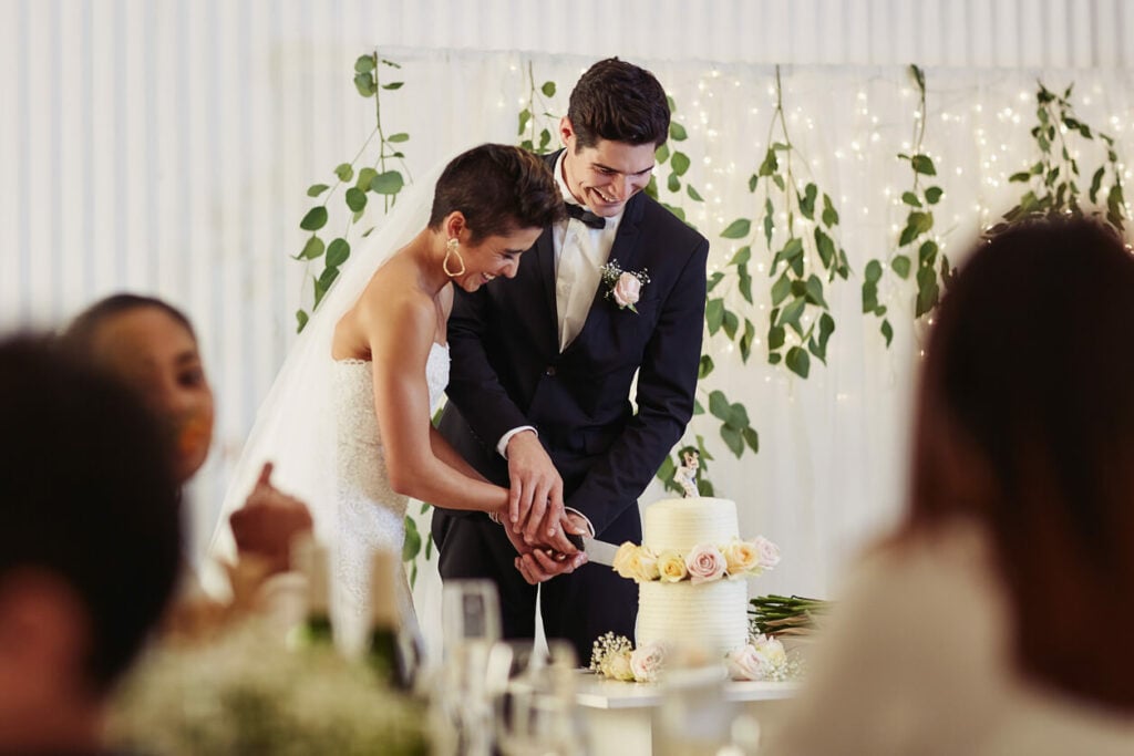 A couple cuts cake while they listen to a song from the best wedding songs playlist