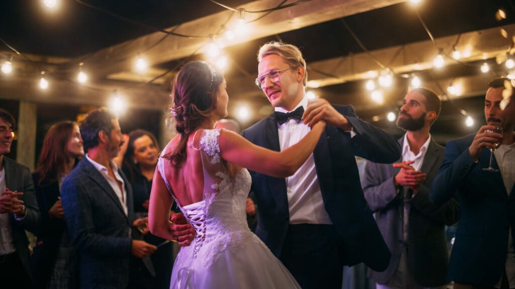A bride in a white dress and a groom in a sharp suit dance